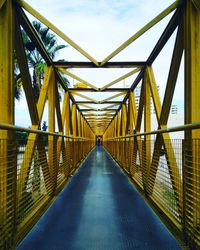 Footbridge leading towards bridge against sky