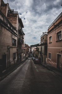 Empty road amidst buildings in city against sky