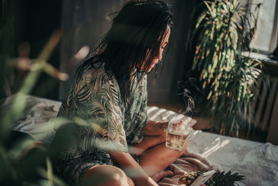 Midsection of woman drinking glass sitting on table