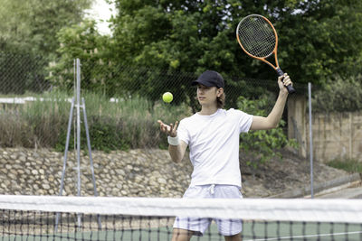 Accurate portrait of a young boy playing tennis serving against his opponent in a tennis match