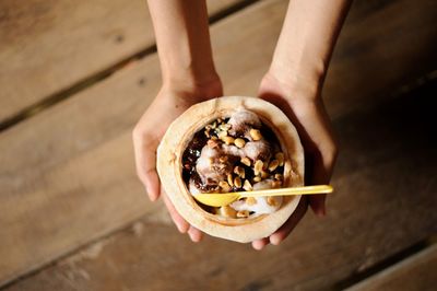 Midsection of person holding ice cream on table