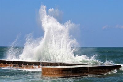 Waves splashing on sea against sky