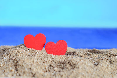 Close-up of heart shape on sand at beach against sky