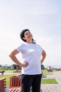 Smiling young woman standing against sky