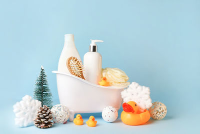 Baby bath cosmetics in toy bathtub with christmas decorations on blue bakground