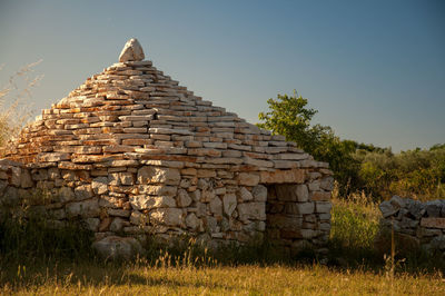 Stone wall on field against clear sky