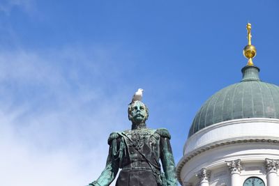 Low angle view of statue of building against blue sky