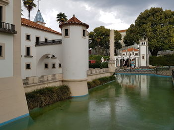 Building by lake against sky in city