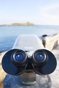 Close-up of coin-operated binoculars at beach against sky