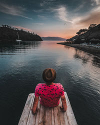 Rear view of woman looking at lake against sky