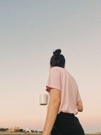 Side view of woman standing against sky during sunset