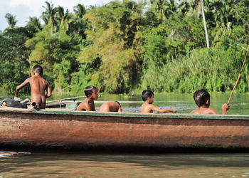 Rear view of men on water against trees