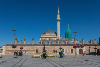 Group of people in front of building against clear blue sky