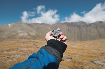 Person holding hands against mountain range