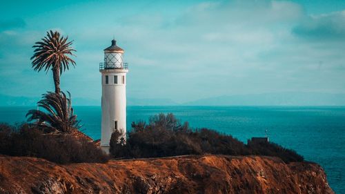 Lighthouse by sea against sky
