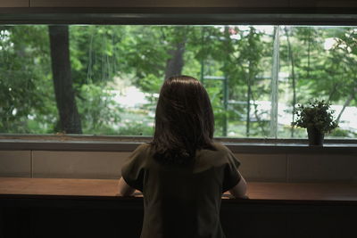 Rear view of woman looking through window