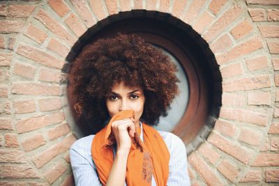 Portrait of young woman against brick wall