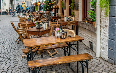 Empty chairs and tables at sidewalk cafe in city