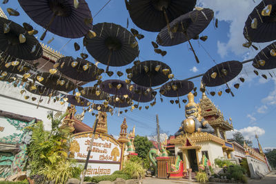 Low angle view of decorations hanging by building against sky