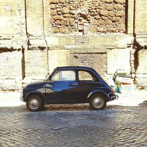 Vintage car parked against brick wall
