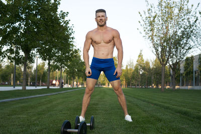 Shirtless muscular man exercising on field