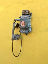 Close-up of old electric lamp against yellow wall