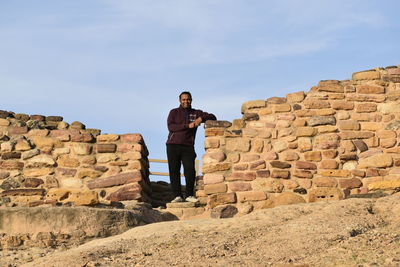 Rear view of man standing on rock against sky near world heritage site harappan city 