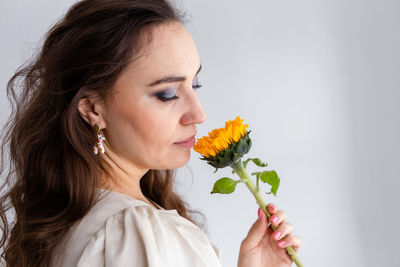 Close-up of woman holding flower against wall