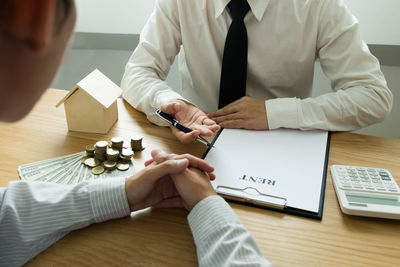 Midsection of couple holding while sitting on table