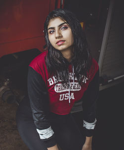 Portrait of beautiful young woman standing against red wall