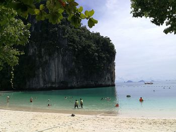 People in sea against rock formation