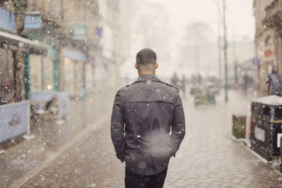 Rear view of man walking on street during winter