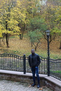 Full length of man standing by railing in forest