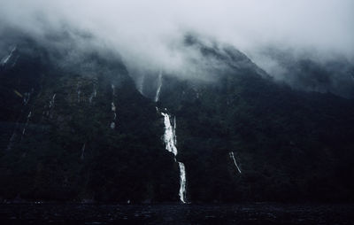 Low angle view of waterfalls in foggy weather at te anau