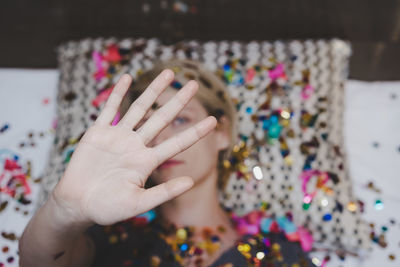 High angle portrait of woman gesturing while lying with multi colored decorations on bed