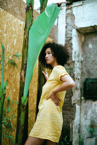 Side view of a young woman standing against wall