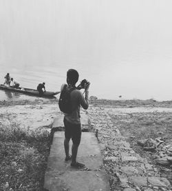 Rear view of woman standing on beach against clear sky