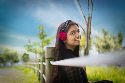 Portrait of young woman standing against plants