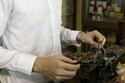 Midsection of man weighing dried food in store