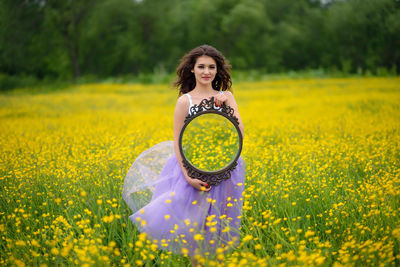 Portrait of woman with yellow flower on field