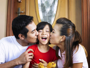 Close-up of parents kissing daughter at home