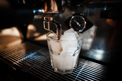 Close-up of coffee pouring in drinking glass at cafe