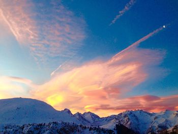 Scenic view of snowcapped mountains against cloudy sky during sunset