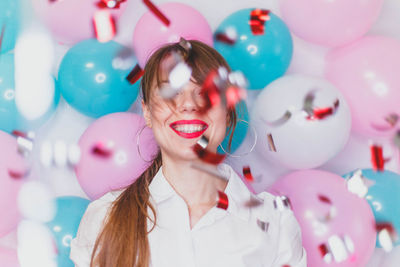 Cheerful young woman with balloons and graffiti in room