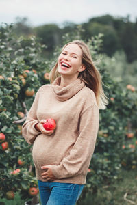 Young woman smiling while standing against trees