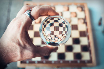 Close-up of man holding crystal ball over chess board