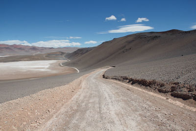 Road leading towards desert against sky