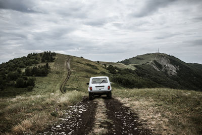 Car on road by mountain against sky