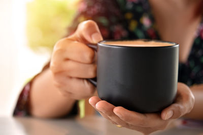 Midsection of woman holding coffee cup