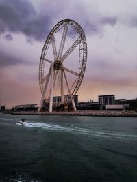 Ferris wheel by sea against sky